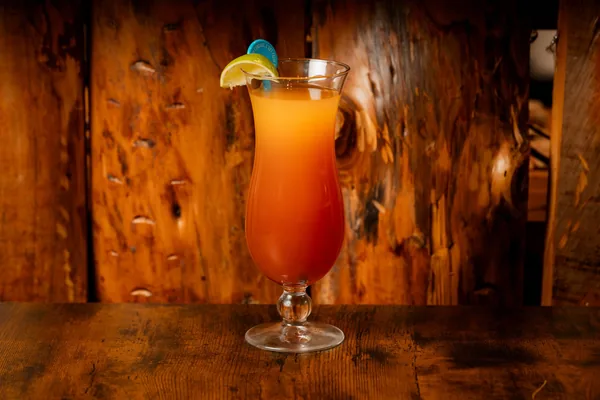 Cocktail orange servi dans un grand verre, tranche de citron vert