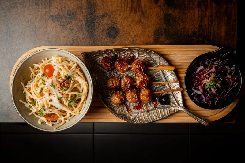 Brochettes de poulet caramélisé servies avec un bol de nouilles à la crème et du chou rouge